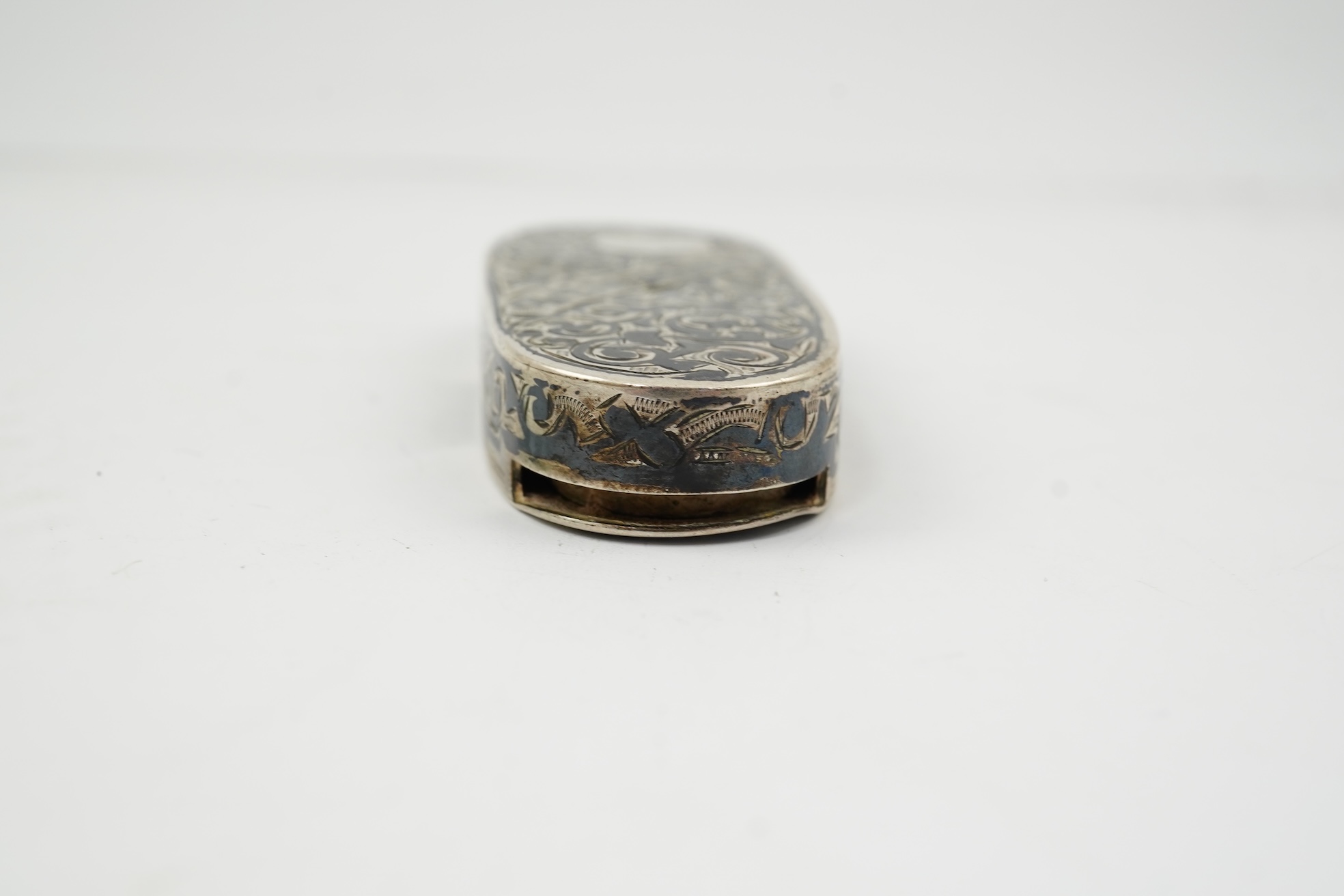 A 19th century Russian silver and niello coin case, of oval form, with Cyrillic inscription and three slide action coin compartments, unknown master, 76mm.
